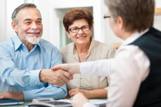 Couple Smiling and Shaking Hands with Agent After Getting Life Insurance in Houston, Clear Lake, Galveston, Friendswood, TX, Manvel